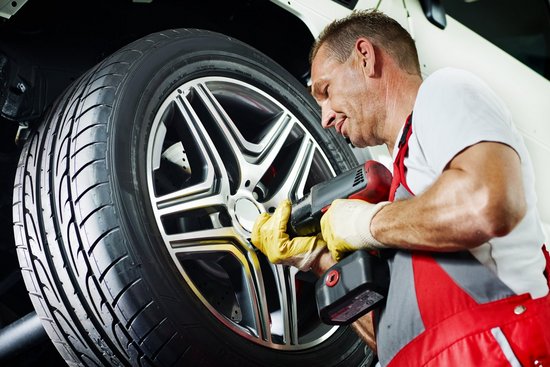 Motor mechanic is changing a tyre with new alu rim